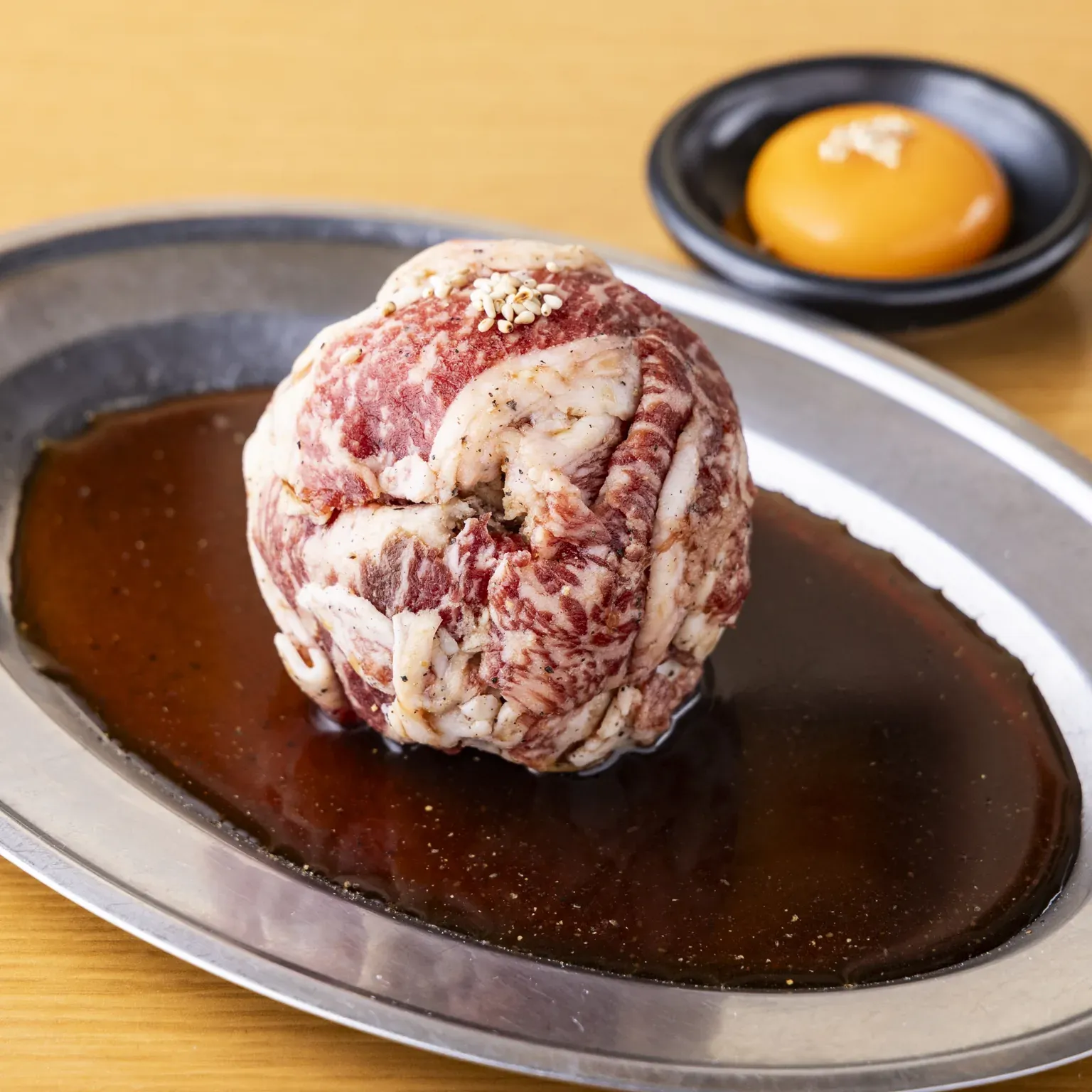タレを張った皿に丸く盛った牛肉と、卵黄の小鉢