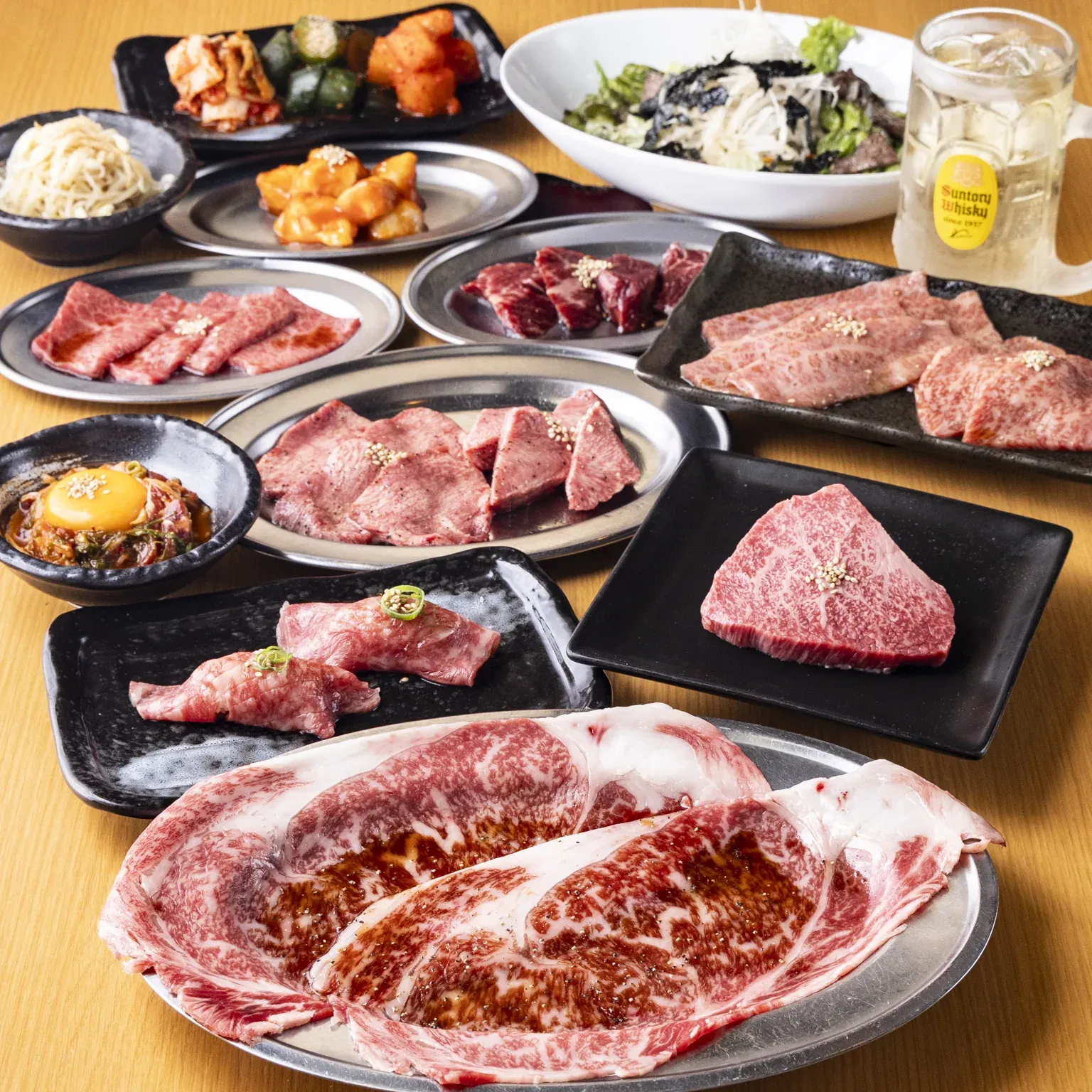 霜降りの牛肉の盛り合わせやキムチ、サラダが並ぶテーブル
