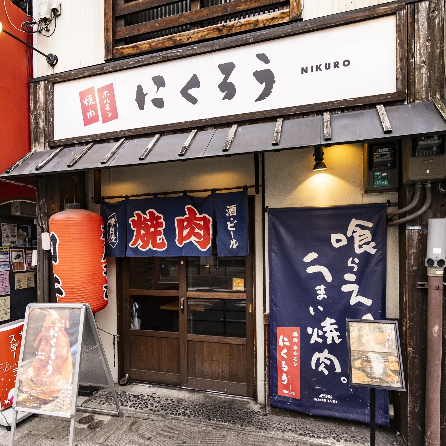 「にくろう」の看板と紺ののれん、赤い提灯が並ぶ京橋店の外観