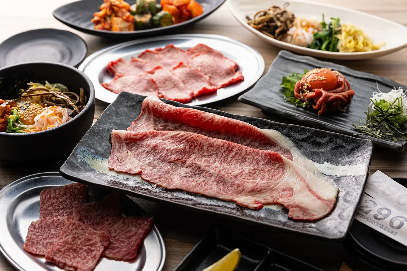 霜降りの薄切り牛肉の大皿と、小鉢やナムルが並ぶテーブル
